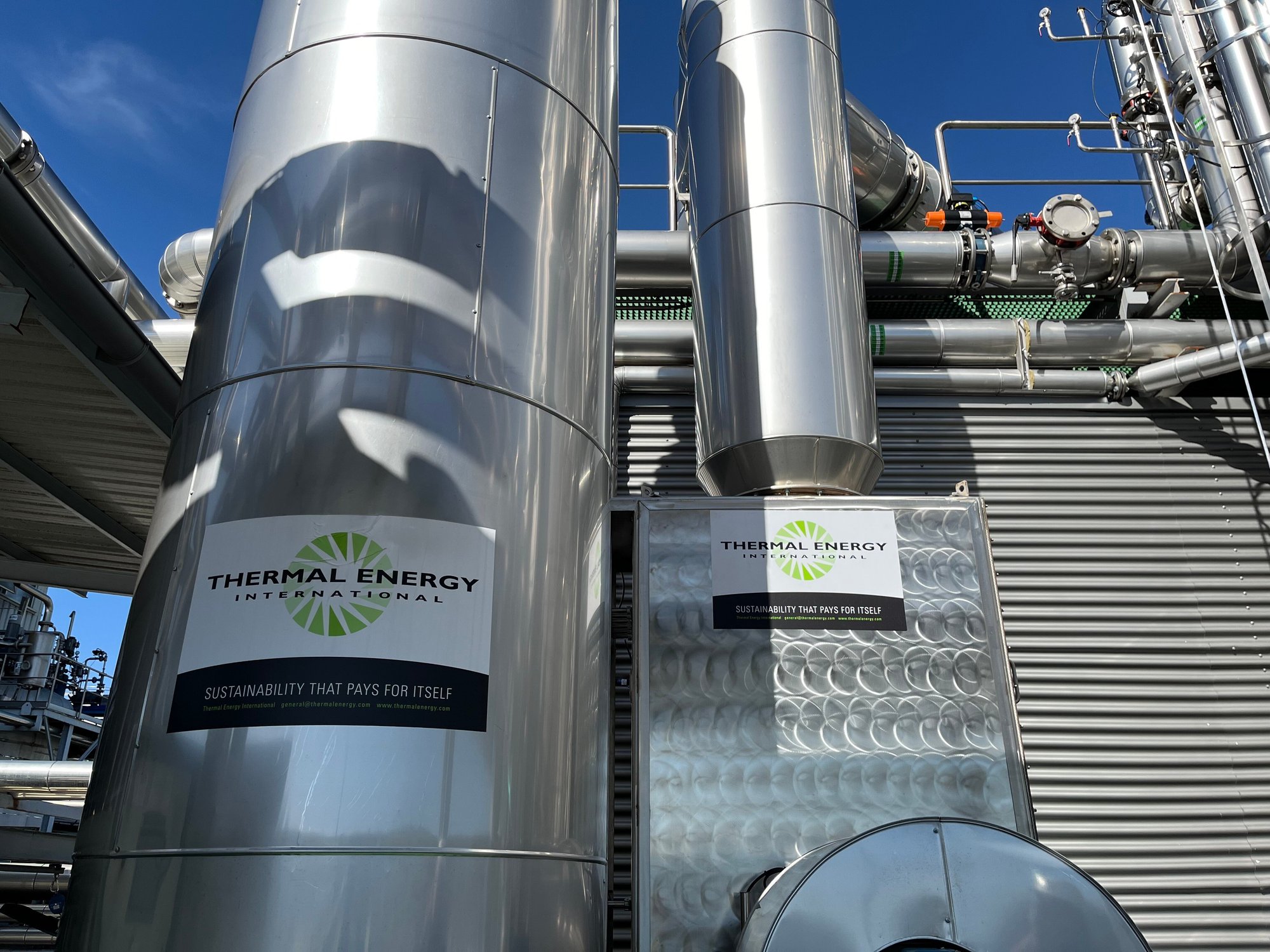 FLU-ACE heat recovery tower beside a HeatSponge unit with Thermal Energy International branding installed at an industrial manufacturing plant