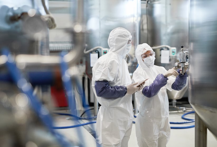 Two pharmaceutical site workers checking an instrument